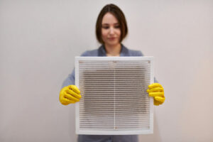 A woman with gloves holding an air filter.