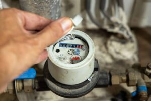 A hand touching a water meter.