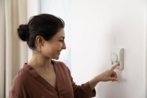 Smiling homeowner changing thermostat settings.